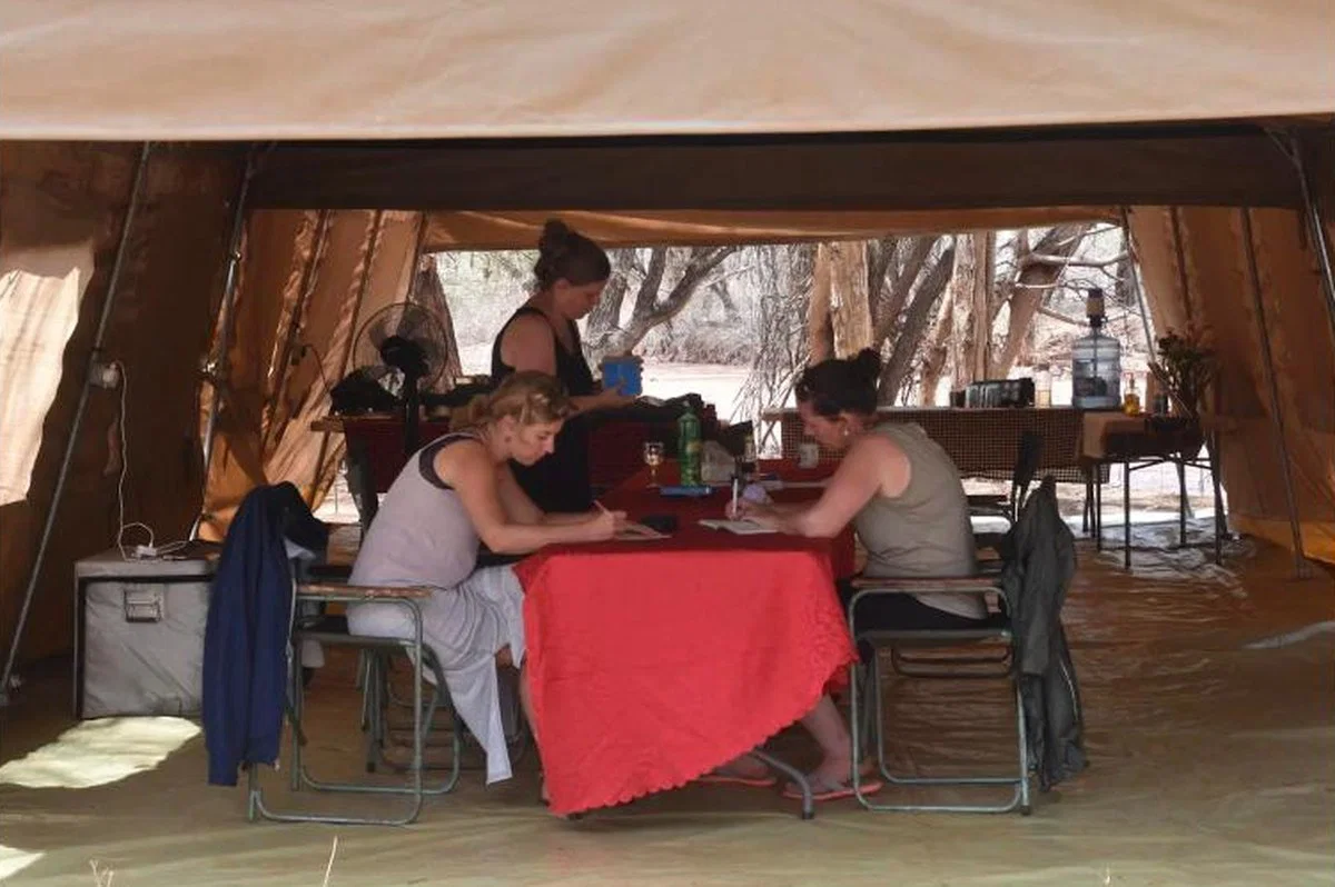Bucket Ministry retreat — guests working together in a Tarpo mess tent