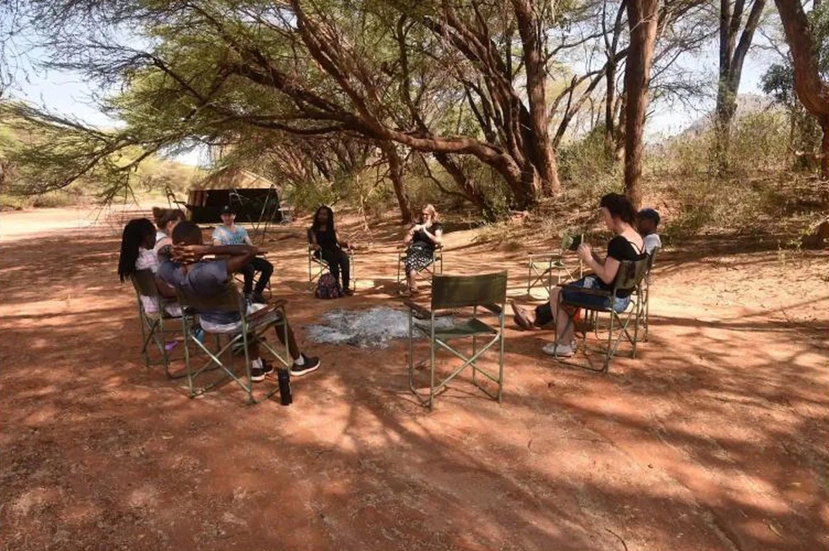 Wild Soul Safari retreat — guests in a circle of safari chairs under acacia shade